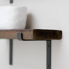 a wooden shelf with two white pillows on it's sides and black metal brackets