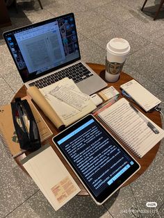 an open laptop computer sitting on top of a wooden table next to a cup of coffee