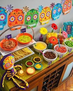 a mexican themed birthday party with food and decorations on the buffet table in front of colorful day of the dead sugar skulls