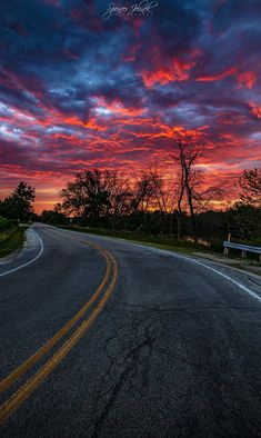 the sun is setting on an empty road