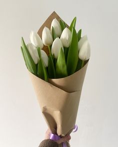 a person holding a bouquet of white tulips