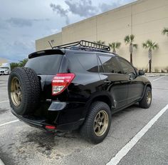 the back end of a black suv parked in a parking lot next to a building