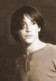 a black and white photo of a young man with short hair wearing a sweater looking at the camera