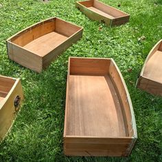 several wooden boats sitting on top of a lush green field