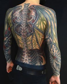 the back of a man's body with tattoos on his upper and lower half