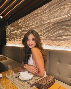 a beautiful woman sitting at a table in a restaurant