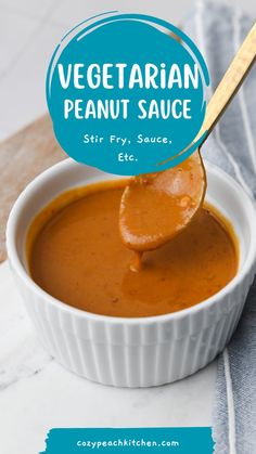 a spoon full of vegatarian peanut sauce on top of a white bowl with a wooden spoon