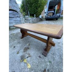 a wooden table sitting on the ground next to a van