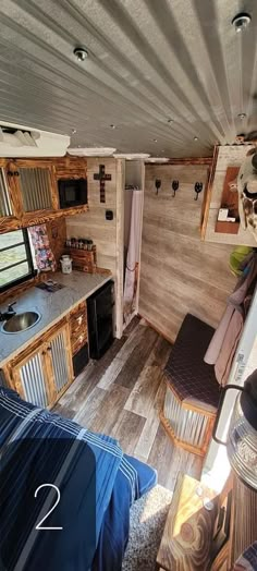 the interior of a mobile home with wood flooring and walls, including a kitchen