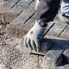 a person with gloves on is standing on bricks