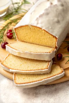 sliced loaf of pound cake with icing and cranberries on wooden platter