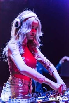 a woman wearing headphones is playing music on a dj's turntable at a concert