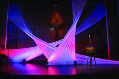 the stage is lit up with purple and blue lights for an artistic performance in front of a cross