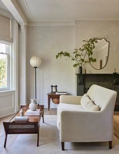 a living room filled with furniture and a fire place in front of a mirror on the wall