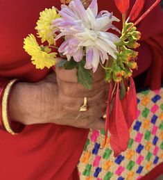 the woman is holding a bouquet of flowers in her hands and wearing a red dress