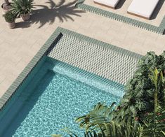 an aerial view of a swimming pool with lounge chairs and palm trees in the background