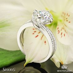 a diamond engagement ring sitting on top of a flower