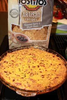 a pie sitting on top of a stove next to a bag of chips and a glass bowl