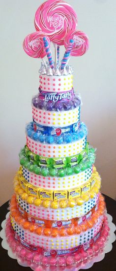 a multi - tiered cake with candy and lollipops on top is shown