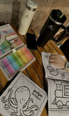 an octopus coloring book and coffee cup on a wooden table with markers, crayons, and pencils