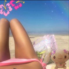 a woman laying on top of a sandy beach next to a stuffed animal