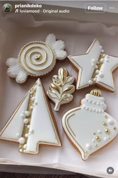 decorated christmas cookies in a box on a wooden table with white and gold trimmings