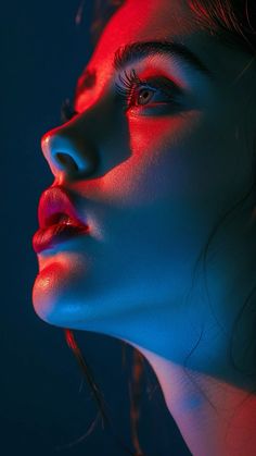 a woman's face is lit up with red and blue light in the dark