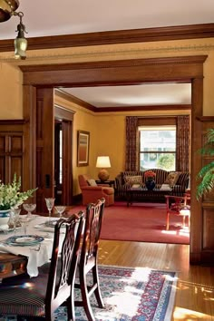 a dining room table with place settings and chairs in front of an open doorway leading to the living room