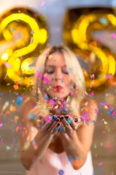 a woman is blowing confetti in front of the numbers 20 and twenty nine