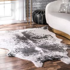 a living room area with a white couch and black and white rug on the floor