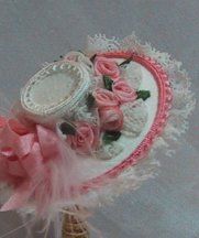 a pink and white hat with flowers on it sitting in a basket next to a wall