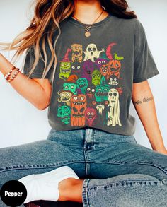 a woman sitting on the floor wearing a t - shirt with skulls and pumpkins