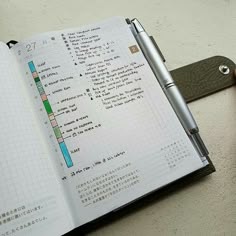 an open notebook with some writing on it and a pen next to it, sitting on top of a table