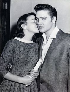 an old black and white photo of a man kissing a woman