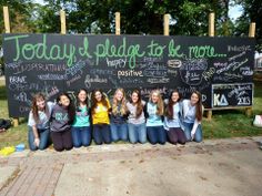 a group of young women sitting next to each other in front of a chalk board