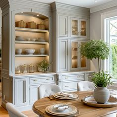 a dining room table and chairs in front of a large window with lots of cupboards