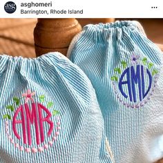 two blue and white striped bags with pink monogrammed letters on them sitting on a wooden table