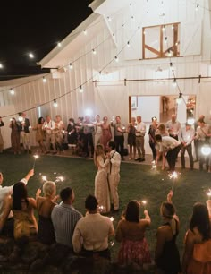 a group of people holding sparklers in front of a barn with lights on it