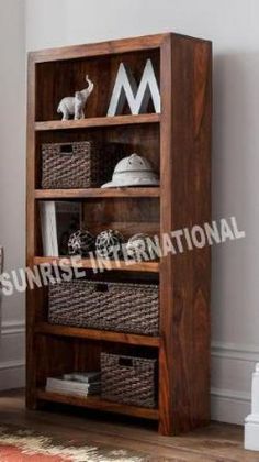 a wooden bookcase with baskets on the bottom and shelves below it, in front of a white wall