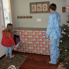 two people in pajamas standing near a christmas tree