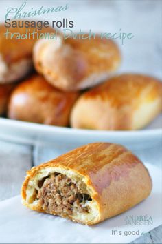 a sausage roll is cut in half on a plate next to some other bread rolls