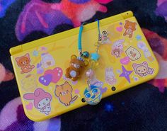 a yellow plastic case with various cartoon characters on it and a keychain attached to it