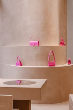 pink purses are lined up on display in a room with white walls and flooring