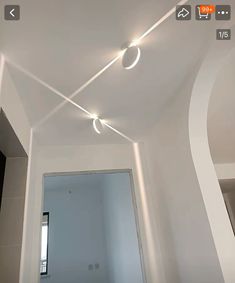 an empty room with some lights on the ceiling and a mirror in front of it