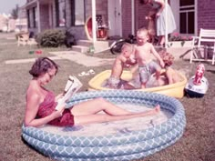 a woman reading a book while sitting in an inflatable pool with two children