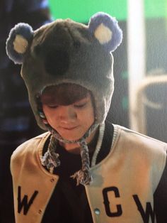 a young boy wearing a bear hat while looking at his cell phone in front of him