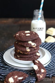 a stack of cookies sitting on top of a white plate next to a bottle of milk