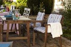 an outdoor dining table with chairs and a towel on it's armrests