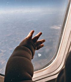 a hand reaching out the window of an airplane