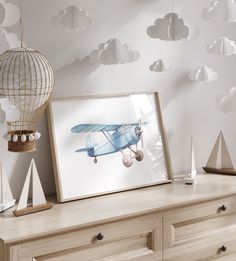 an airplane is hanging on the wall next to a wooden dresser and some white clouds